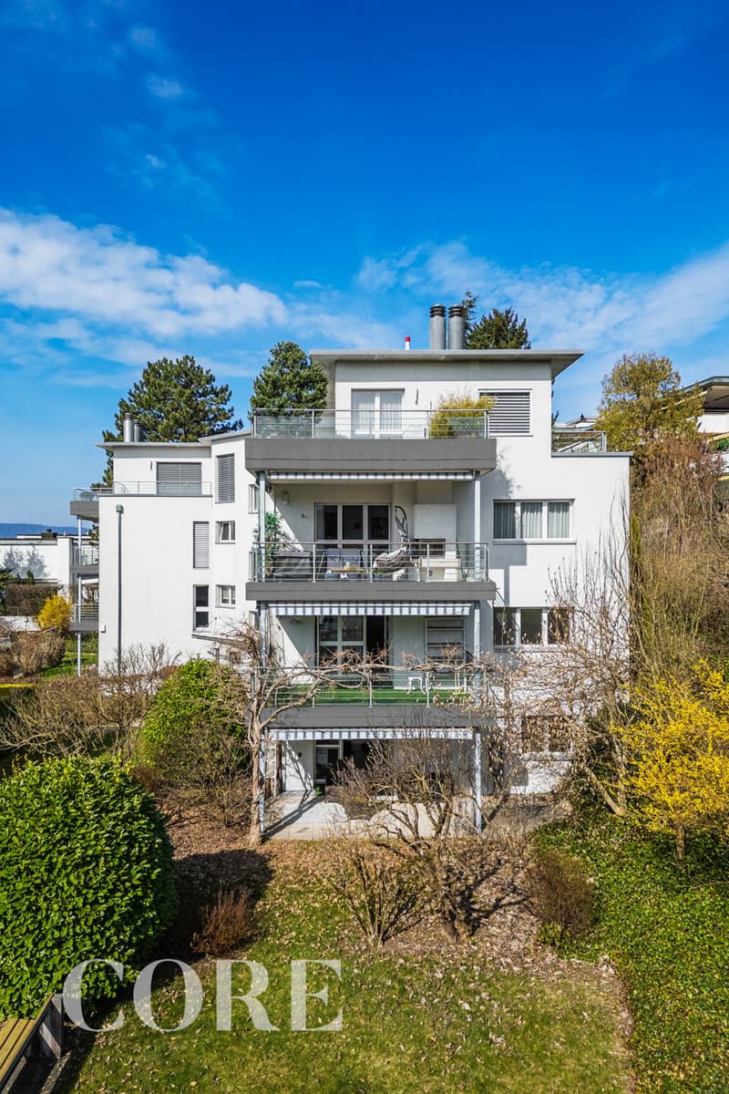 3 story white house, multiple balconies, garden, trees