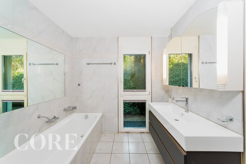 Bathroom with bathtub, sink, mirror, and glass door to the outside
