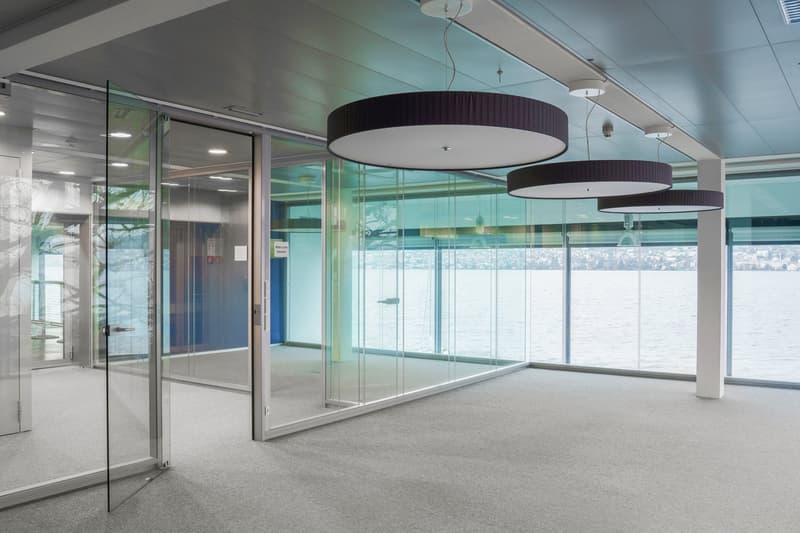 empty meeting room with glass walls and doors, panoramic view of the lake, suspended round lights
