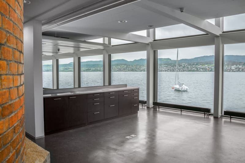 empty room with grey flooring, large windows, view over lake, sailboat outside
