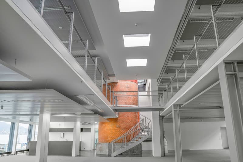 Open space with high ceilings, metal railings, brick chimney, spiral staircase, large windows, industrial design
