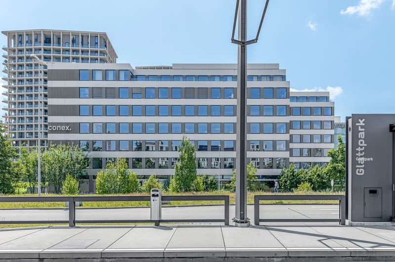 Multi-story building, modern architecture, multiple windows, signage, parking area