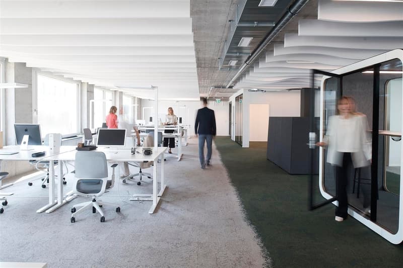 modern office space with white desks, gray office chairs, monitors, and office equipment.