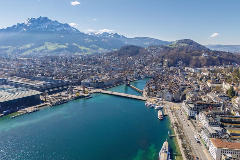 Cityscape of Lucerne with mountains, lake, buildings, bridge, and boats