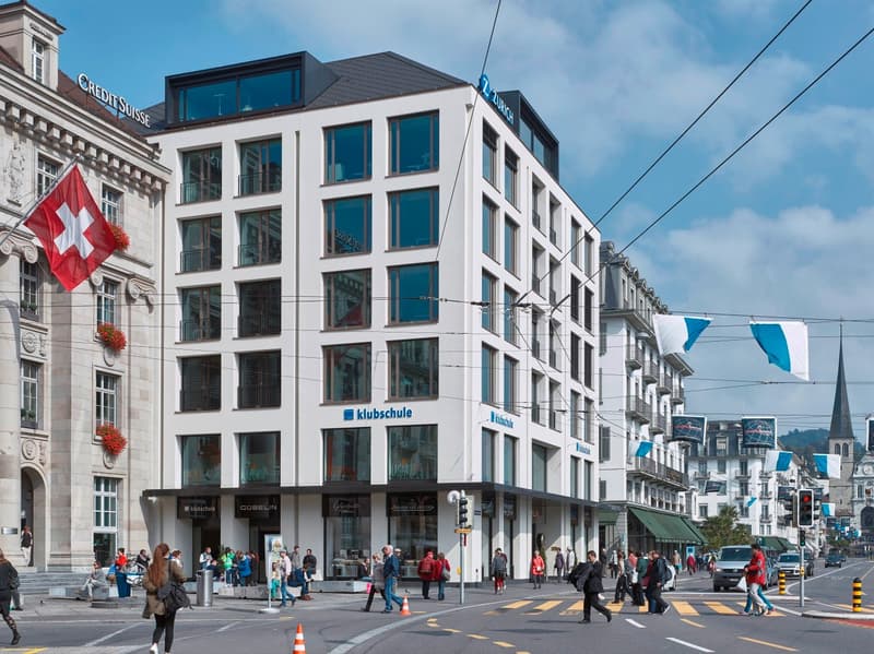Modern building, 5 floors, white exterior, blue signage, glass windows, located in a city