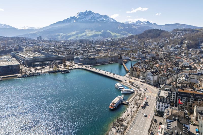 Cityscape with a river, mountains, buildings, and boats