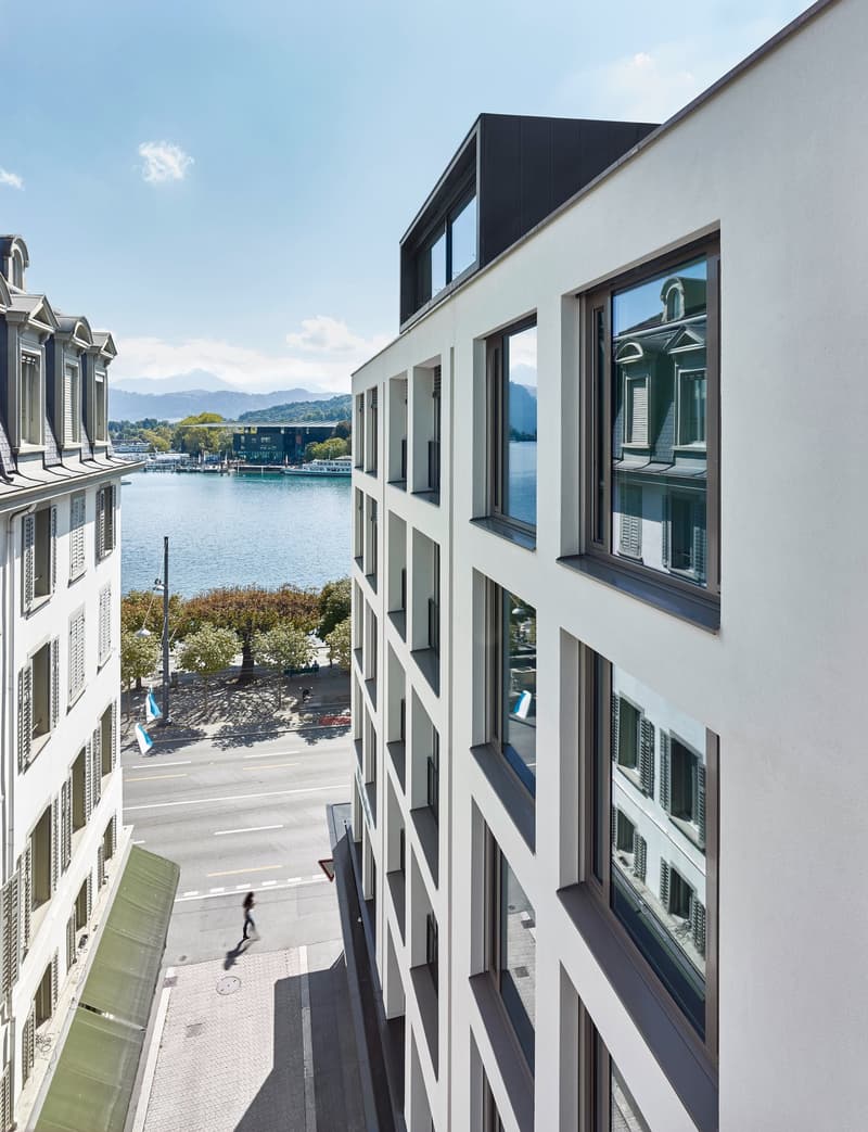 Modern building with glass windows, white walls, view of a lake and mountains