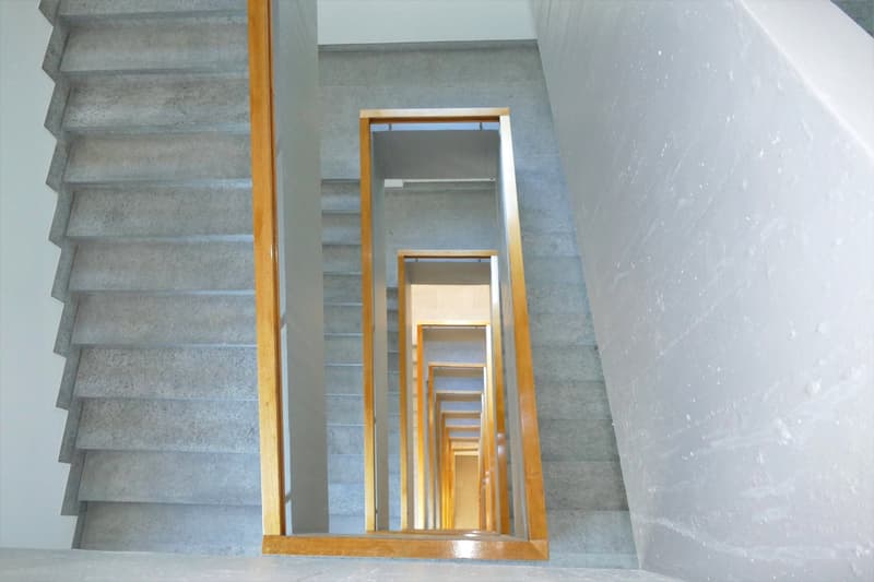 Concrete steps, wooden handrails, staircase leading to different floors