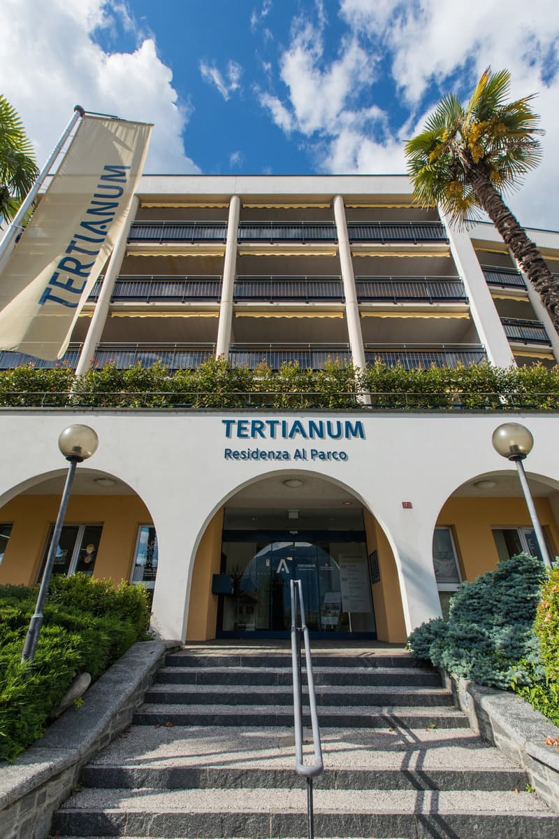 multi-story building, entrance, staircase, flag, palms, entrance sign