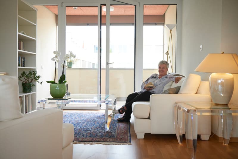 sliding door leading to balcony, modern sofa, carpet, glass coffee table, floor lamps, side tables