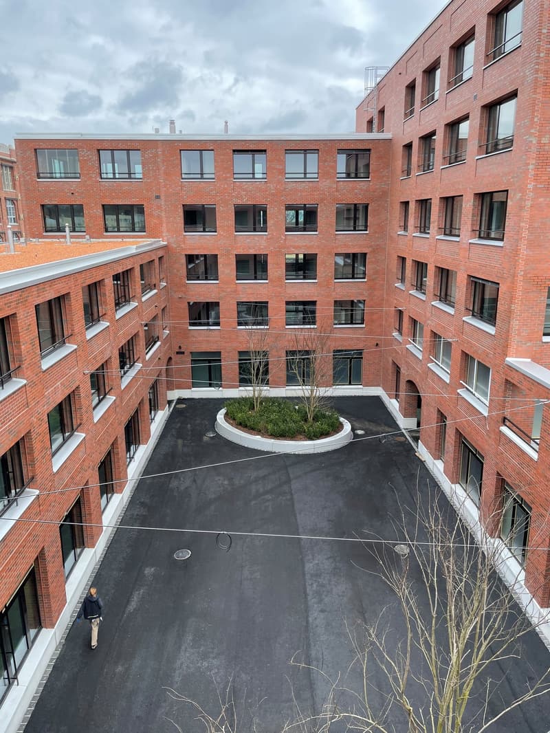 3 story brick building, multiple windows, large courtyard, green center