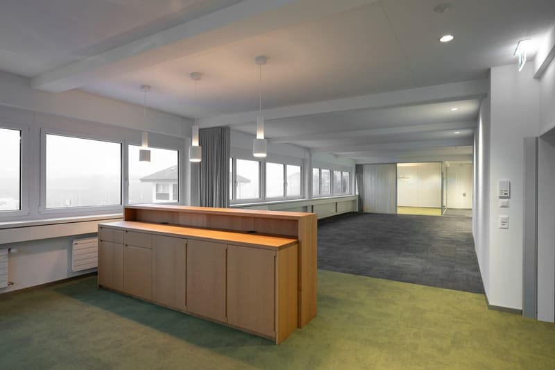 Modern empty office, large windows, white walls, wooden desk, gray carpet, hanging lights