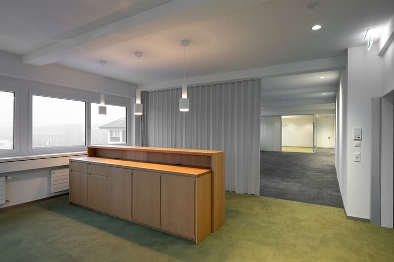 wooden counter, gray curtains, bright room, suspended lights, gray carpet, radiators