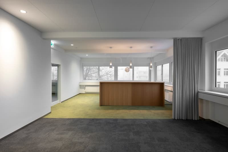 Empty room, white walls, grey carpet, wooden desk, windows, green flooring, modern design, pendant lights