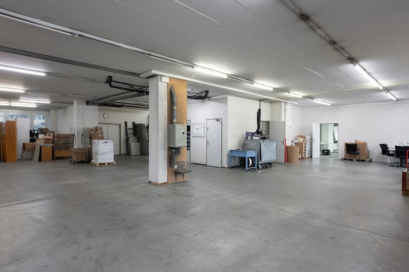 Empty room with concrete floor, white walls, fluorescent lighting, various items and materials