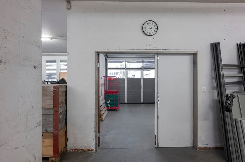 Empty room, concrete floor, white walls, clock, trolleys, and wooden pallets.