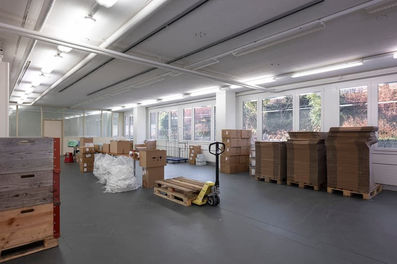 industrial space with boxes and pallet, large windows, warehouse cart, grey floor