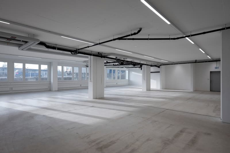 Empty, large parking lot with windows, pipes on ceiling