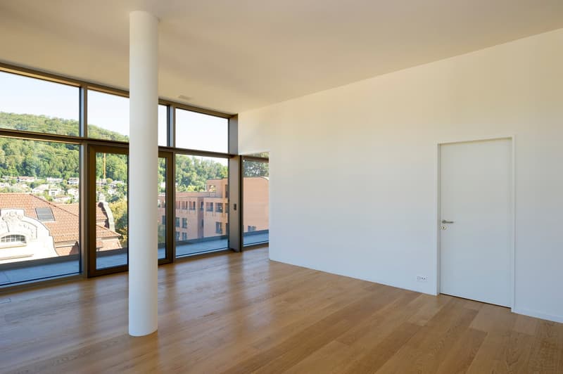 Spacious room with large windows, wooden floor, white walls, open space, and a door