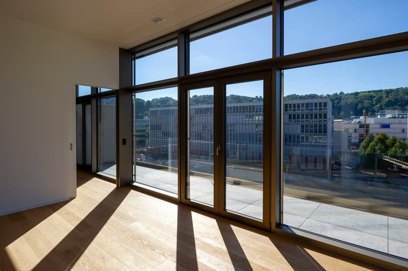 empty room with wooden floor, large glass windows, and wooden sliding doors leading to a balcony