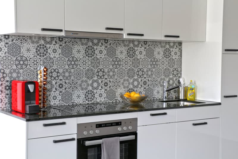 white cabinets, black countertops, gas stove, oven, bowl of lemons, sink, faucet, cleaning products, kitchen tools