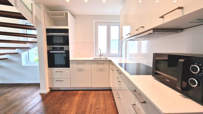 White cabinets, modern appliances, tiled floor, wooden countertop, built-in ovens, under cabinet lights