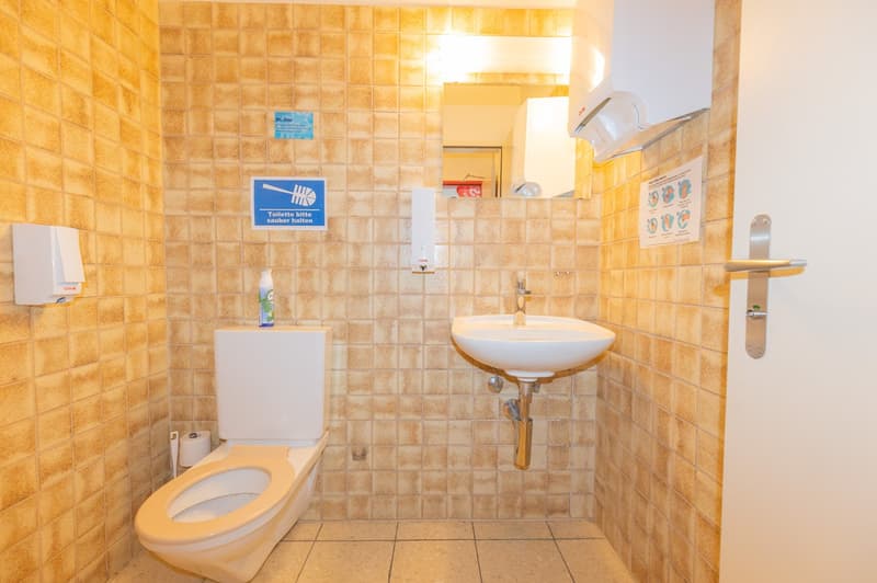 small bathroom with toilet, sink, and tiled walls