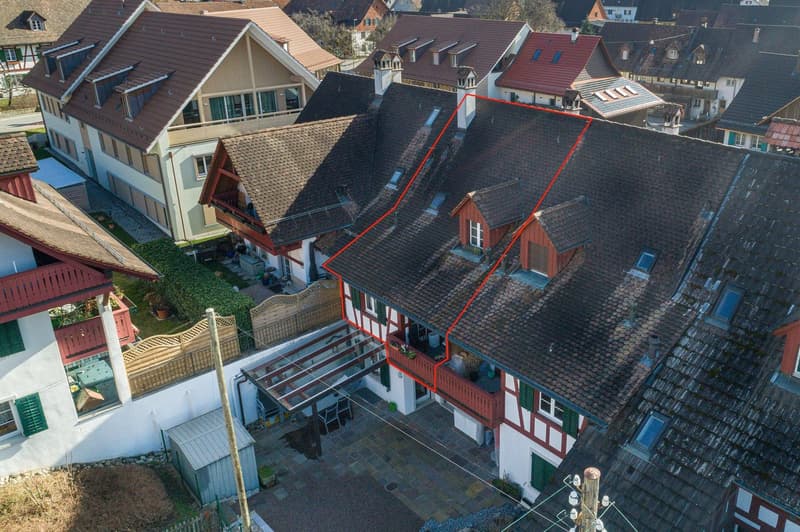 House in village, brown roof, balconies, surrounded by other houses