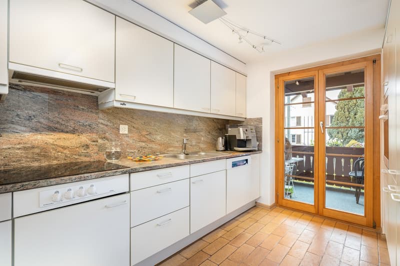 kitchen with white cupboards, granite countertop, dishwasher, gas stove, coffee machine, balcony with table and chairs
