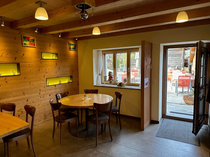 Cozy dining area with wooden walls, round wooden table, leather chairs, and large windows overlooking a balcony or terrace area.