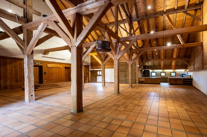 Open space, wooden trusses, tiled floor, wooden walls, hanging pot, kitchen area