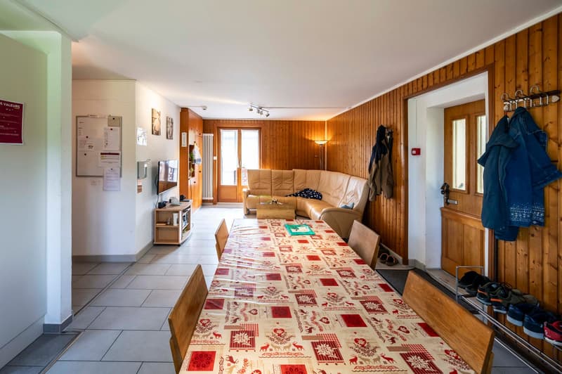 dining room, white tiles, wooden dining table, chairs, TV on wall, radiator, couch