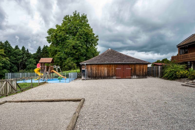 Shed, tree, fenced play area with slides, gravel driveway