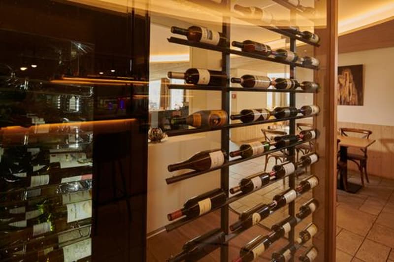 wine rack, tables, chairs, artwork on the wall, tiled floor