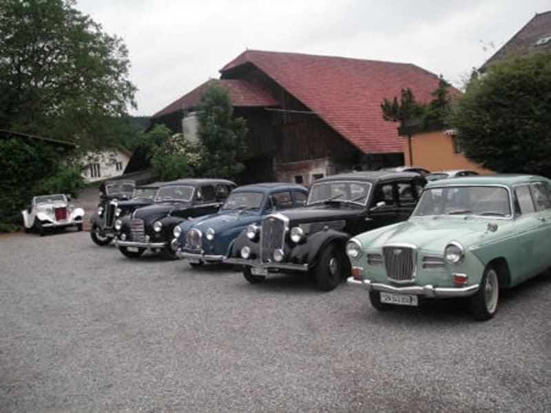Classic cars parked in front of a house with a red roof