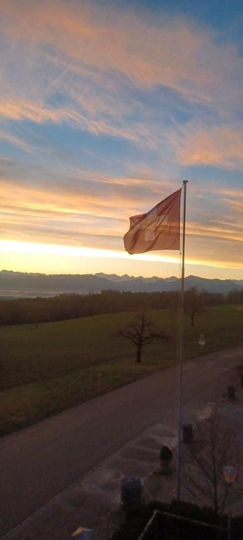 Sunset over a field with a flagpole