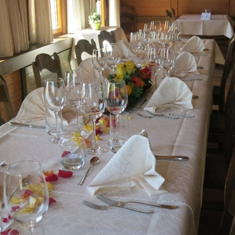 Dining room with long table, wine glasses, forks, knives, spoons, and napkins