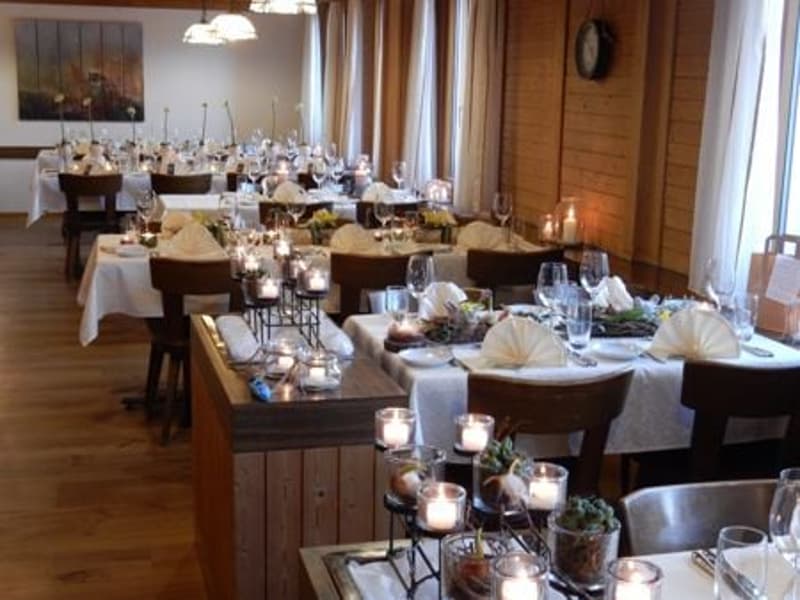 A restaurant with wooden walls, wooden floors, and a dining area with tables and chairs set up for a meal.