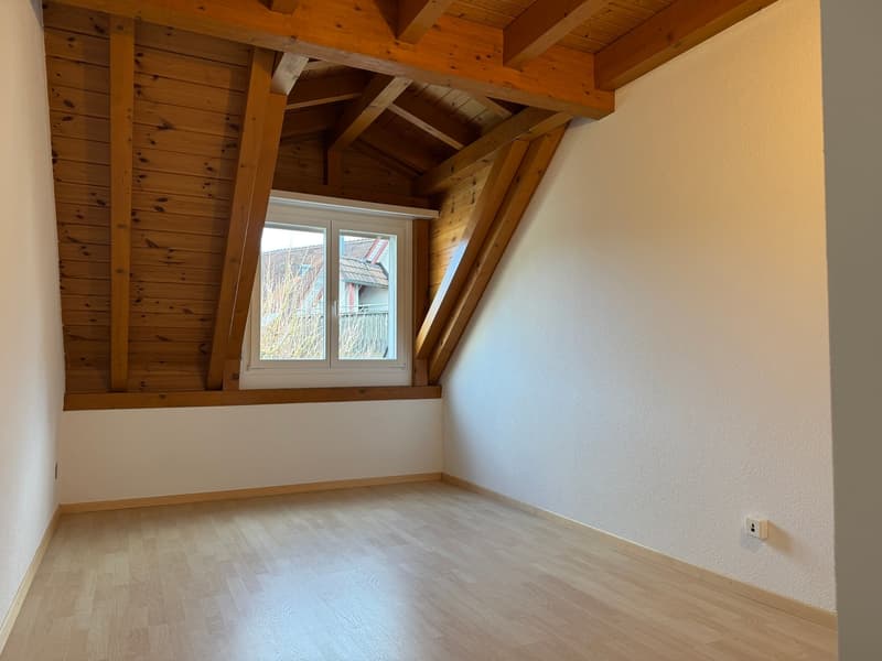 Wooden exposed beam ceiling, white walls, window, wooden floor, power outlet