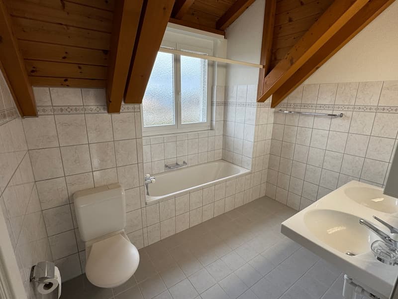 Bathroom: bathtub, toilet, two sinks, towel rack, tiled floor, wooden ceiling