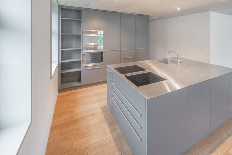 Stainless steel island countertop, integrated ovens, stainless steel appliances, hardwood floors, gray cabinetry, modern design, sink with faucet, ample storage, open shelving