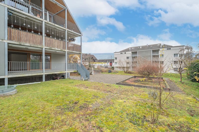 Apartment building, balcony on the first floor, grassy lawn, raised ground floor