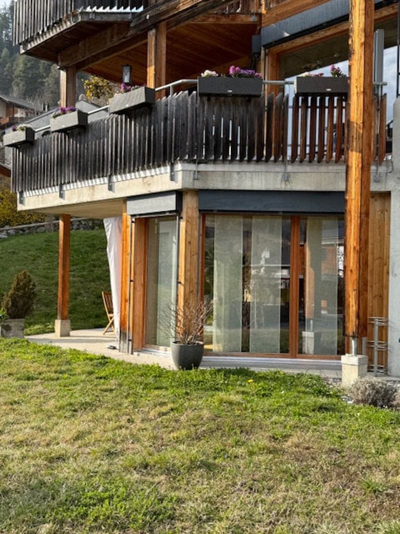 2 story house, wooden exterior, balcony with railings, glass doors, potted plants, wooden chair, grassy lawn