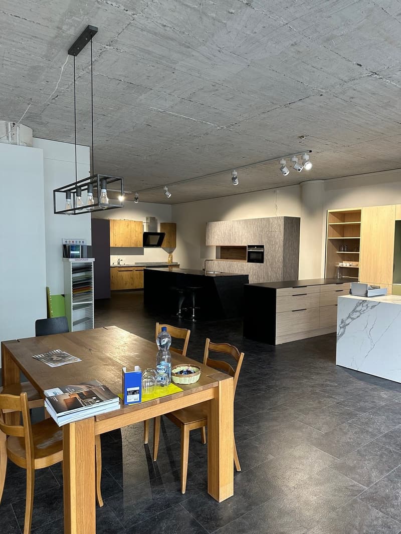 Open floor plan, central dining table, modern wooden cabinets, island with seating, industrial ceiling, track lighting, kitchen with appliances