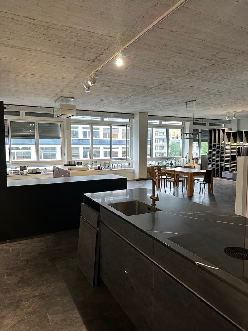 Modern kitchen with marble countertops, stainless steel faucet, gas stove, island with sink, dining table, modern cabinets, windows with a city view.