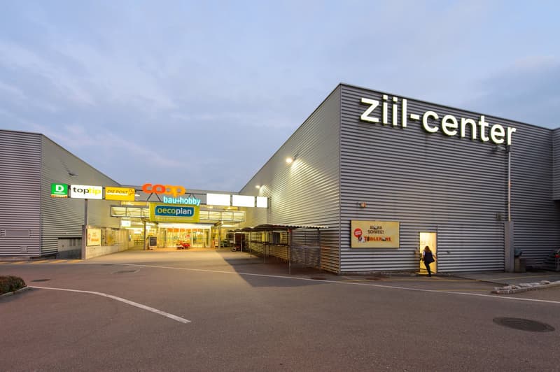 Commercial building, elevated ground, signage, wide parking area, multiple shops