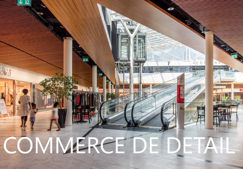 Indoor mall with escalators, shops on both sides, seating area, and an outdoor sign