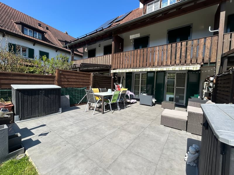 Outdoor dining area with table and chairs, wooden storage box, wooden fence, wooden deck, potted plants, solar panels on the roof
