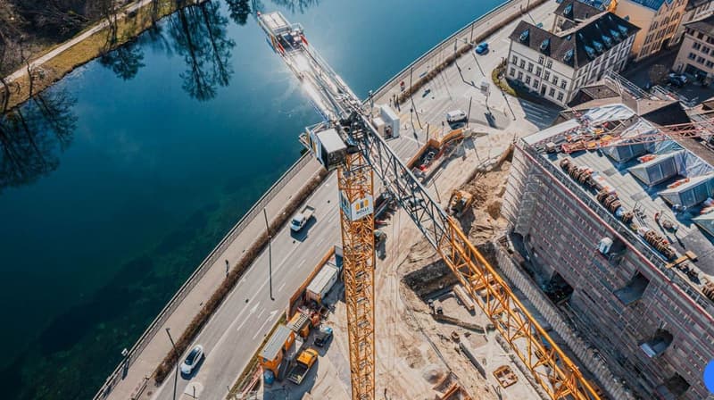 construction site, cranes, vehicles, workers, construction area, buildings, road, body of water, greenery