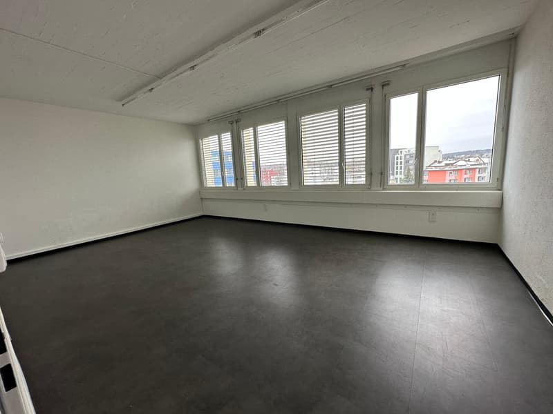 spacious empty room with windows, dark floor, white walls